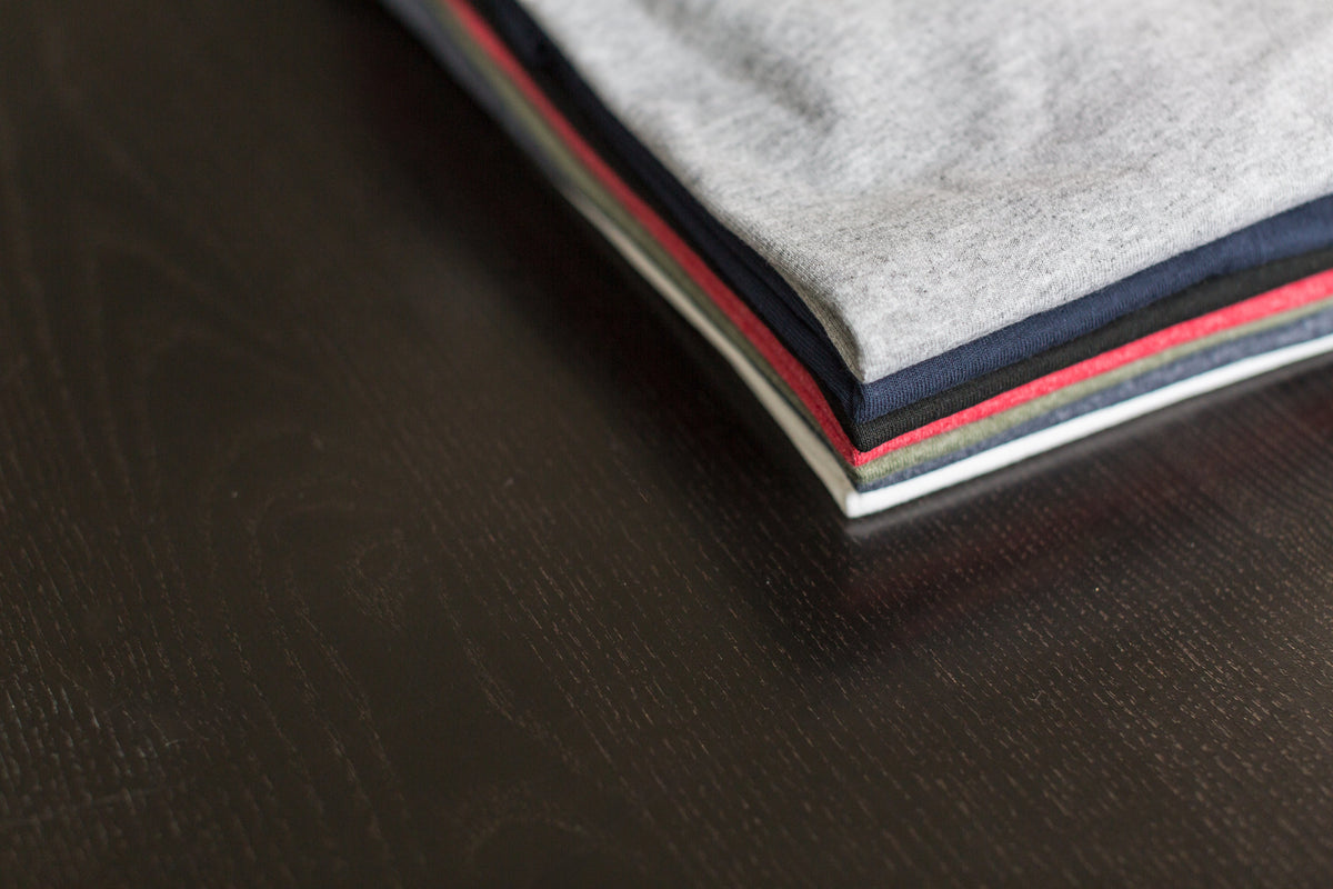 Folded custom printed t-shirts on a table at the Threadmates studio in River Edge, NJ